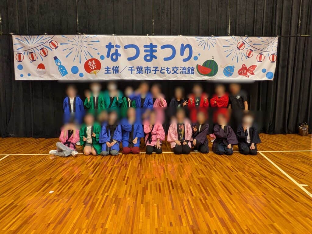 なつまつりを終え、横断幕の下で記念撮影をする生徒たち